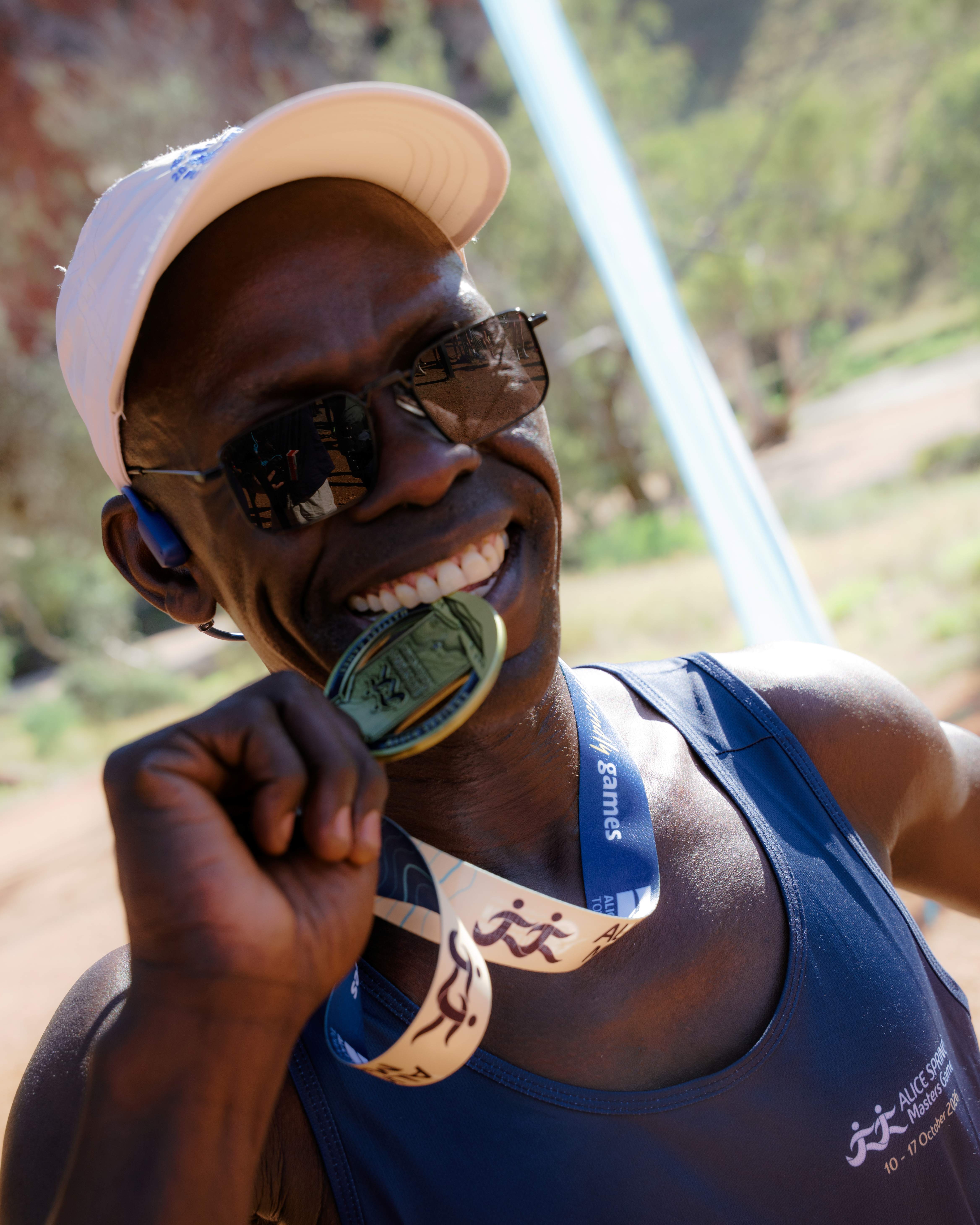 A competitor from the half marathon sinks his teeth into his Gold Medal at the Alice Springs Masters Games 2026
