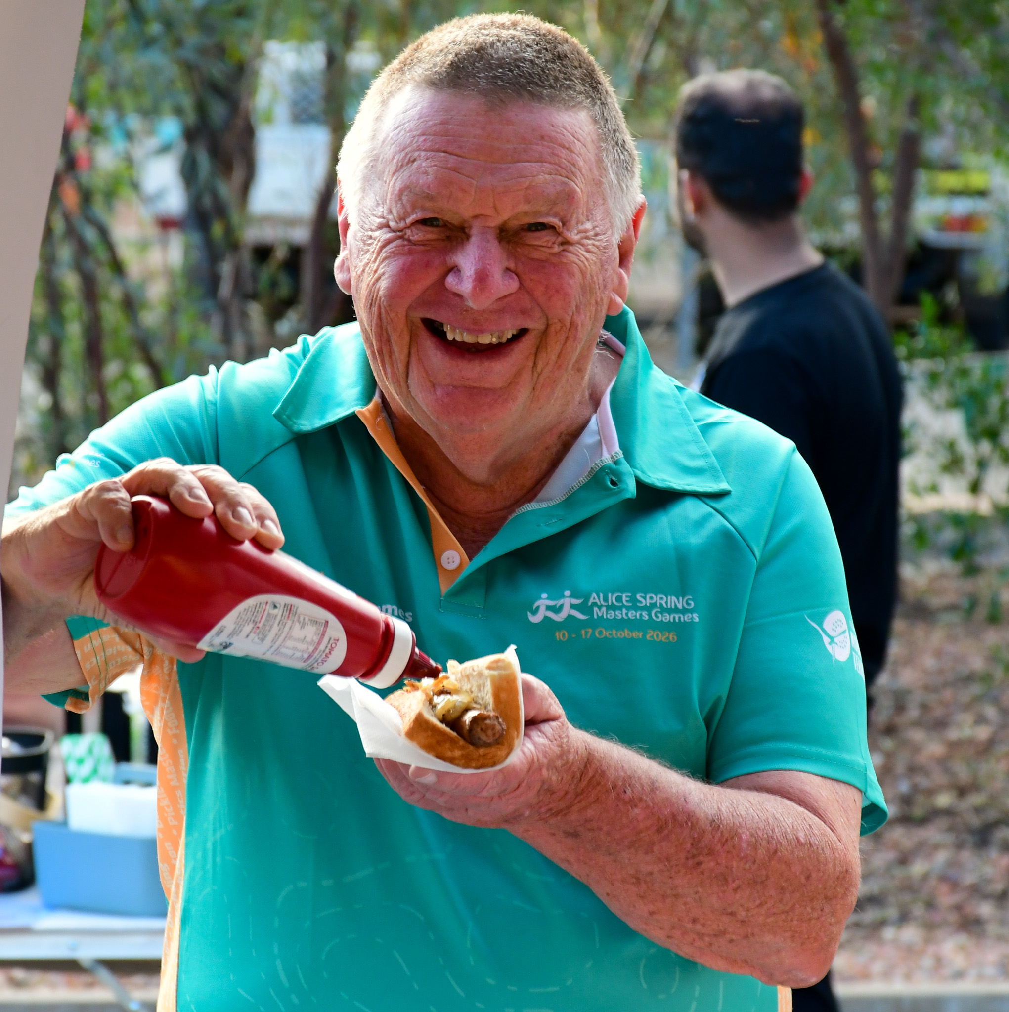 A volunteer tucks into a snag at the Alice Springs Masters Games 2026